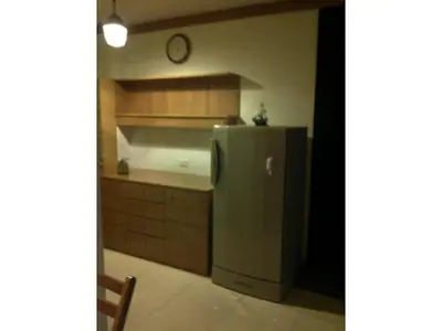 a kitchen with a refrigerator and a clock on the wall at IMPACT Don Mueang Bangkok Guest House in Nonthaburi