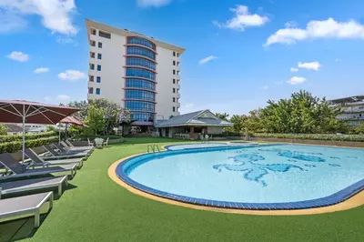 a large swimming pool with lounge chairs and a tall building at Town in Town Hotel Bangkok in Bangkok