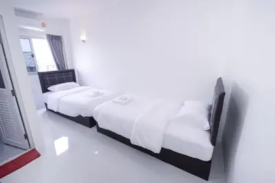 a bedroom with two beds and a television in it at U-need Guesthouse95 in Bangkok