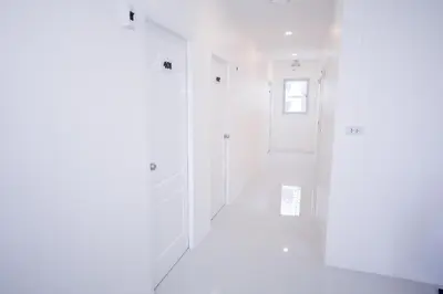 a white hallway with white walls and a window at U-need Guesthouse95 in Bangkok