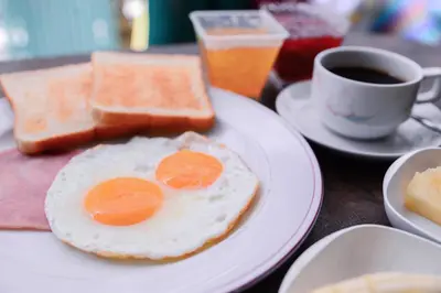 a breakfast plate with eggs and toast and a cup of coffee at U-need Guesthouse95 in Bangkok