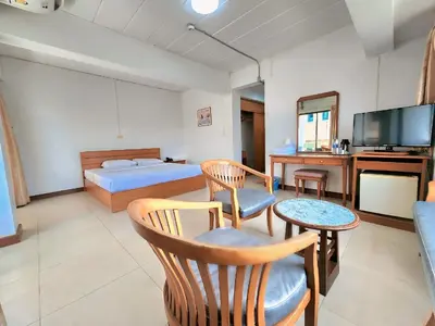 a bedroom with a bed and a tv and a table at Siam Palace Hotel in Bangkok