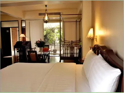 a bedroom with a white bed and a living room at Sourire at Rattanakosin Island Hotel in Bangkok