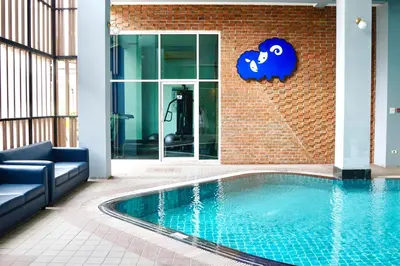 a swimming pool in front of a brick building at Kokotel Bangkok Dheva Thonglor in Bangkok