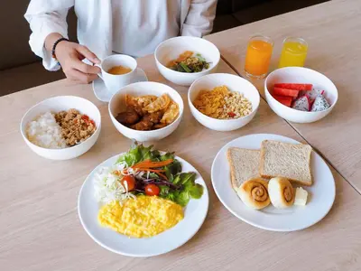 a table with plates of food and bowls of food at Kokotel Bangkok Dheva Thonglor in Bangkok