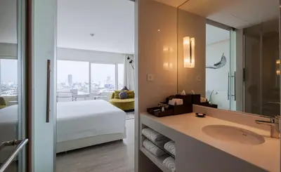 a bathroom with a sink and a bed and a mirror at Centara Watergate Pavilion Hotel Bangkok in Bangkok