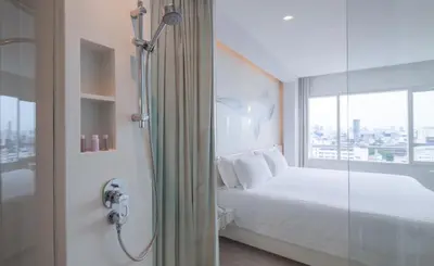 a bathroom with a shower and a bed and a window at Centara Watergate Pavilion Hotel Bangkok in Bangkok