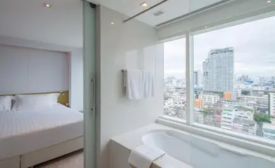 a bedroom with a bed and a bath tub next to a window at Centara Watergate Pavilion Hotel Bangkok in Bangkok