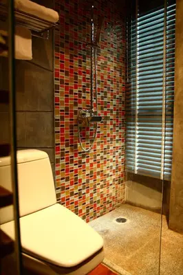 a bathroom with a toilet and a glass shower at The Fusion Suites in Bangkok