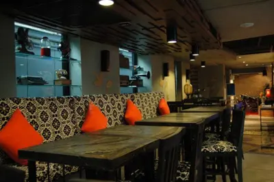 a row of wooden tables in a restaurant with orange pillows at The Fusion Suites in Bangkok