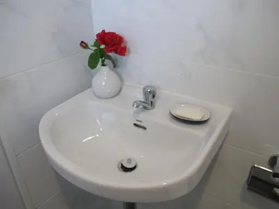 a white sink with a vase with a red rose in it at J.K. Mansion in Bangkok