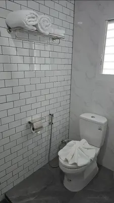 a white bathroom with a toilet and towels at J.K. Mansion in Bangkok
