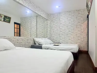 a bedroom with two beds and a brick wall at Baan33 check in by yourself code inbox 4fl behind Amazon cafe in Bangkok