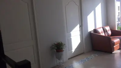 a living room with a chair and a plant next to a door at TEAK VILLA in Bangna