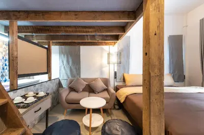 a room with a bed and a couch and a table at Tepbunthom Hostel in Bangkok