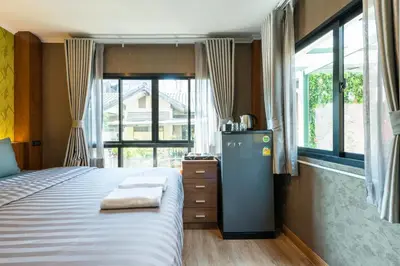 a bedroom with a large bed and a large window at Tepbunthom Hostel in Bangkok