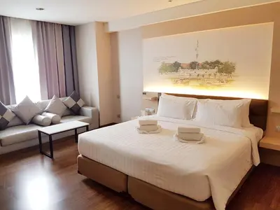 a hotel room with a large bed and a couch at Parinda Hotel in Bangkok