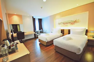 a hotel room with two beds and a desk at Parinda Hotel in Bangkok