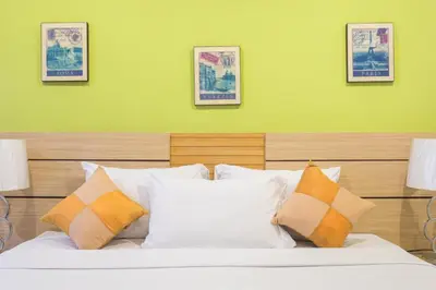a bedroom with a bed with white and orange pillows at The Legacy Convention Hotel in Nonthaburi