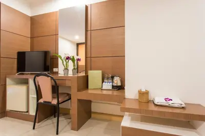 a room with a desk with a tv and a chair at The Legacy Convention Hotel in Nonthaburi