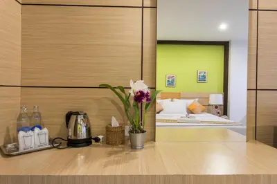 a bedroom with a bed and a table with flowers at The Legacy Convention Hotel in Nonthaburi
