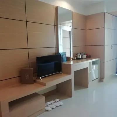a room with a television and a desk with a mirror at The Legacy Convention Hotel in Nonthaburi