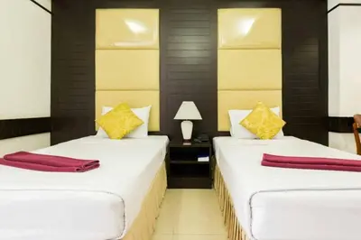 two beds in a hotel room with red and yellow pillows at The Legacy Convention Hotel in Nonthaburi