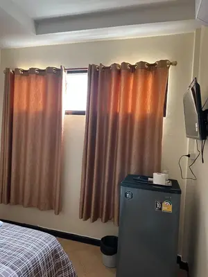 a room with a window with curtains and a television at Orchid House in Bangkok