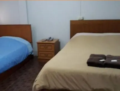 a hotel room with two beds and a night stand at White Orchid Inn II in Bangkok