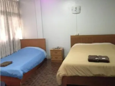 a bedroom with two beds and a dresser at White Orchid Inn II in Bangkok