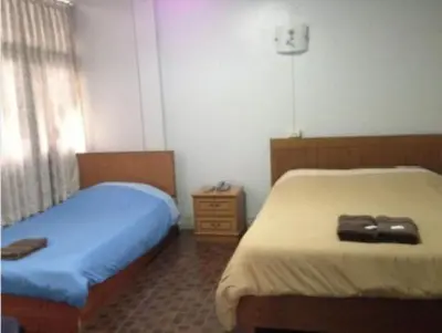 a bedroom with two beds and a dresser at White Orchid Inn I in Bangkok