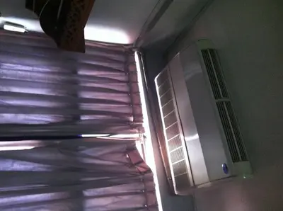 a refrigerator with a window with blinds on it at White Orchid Inn I in Bangkok