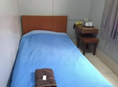 a small bedroom with a blue bed and a desk at White Orchid Inn I in Bangkok