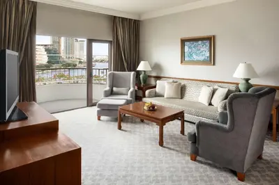 a living room with a couch and two chairs and a television at Shangri-La Bangkok in Bangkok