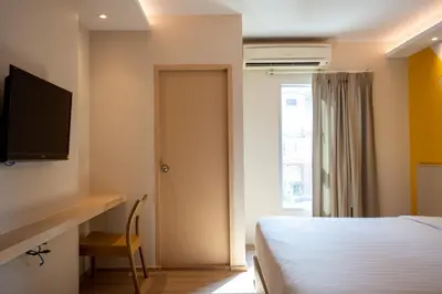 a bedroom with a bed and a desk and a television at Lemontea Hotel Bangkok in Bangkok