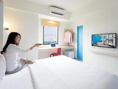 a woman is sitting on a bed in a hotel room at HOP INN Chaengwattana in Nonthaburi