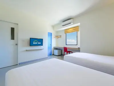 a hotel room with two beds and a flat screen tv at HOP INN Chaengwattana in Nonthaburi
