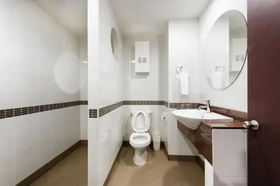 a bathroom with a toilet and a sink and a mirror at Capital Mansion - SHA Certified in Bangkok