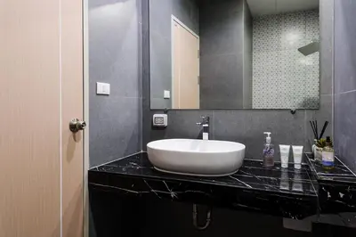 a bathroom with a white sink on a black counter at College Haus Rangnam in Bangkok