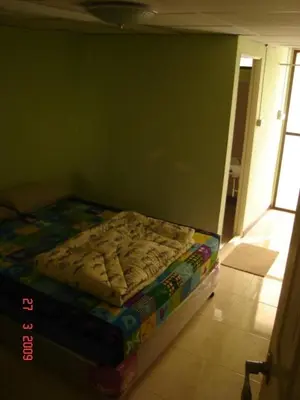 a small bed in a room with a green wall at Kaset Guesthouse in Bangkok