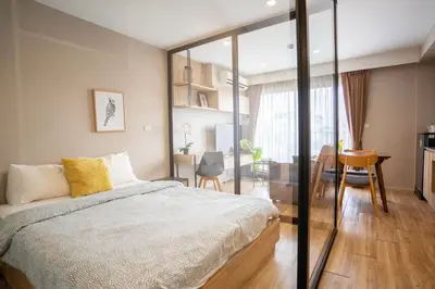 a bedroom with a large bed and a dining room at Blossom Sathon Condo in Bangkok