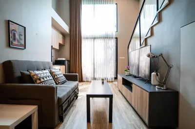 a living room with a couch and a tv at Blossom Sathon Condo in Bangkok
