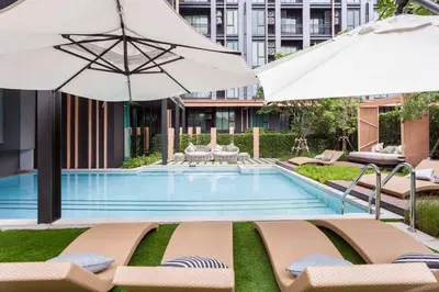 a swimming pool with lounge chairs and umbrellas at CBD Asoke/Nana/Ploenchit +2 mins to Terminal 21 in Bangkok