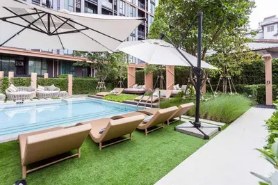 a pool with chairs and umbrellas next to a building at CBD Asoke/Nana/Ploenchit +2 mins to Terminal 21 in Bangkok
