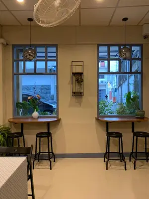 two windows in a room with stools and plants at Achcha hotel - itsaraphap MRT station - Wat Arun in Bangkok