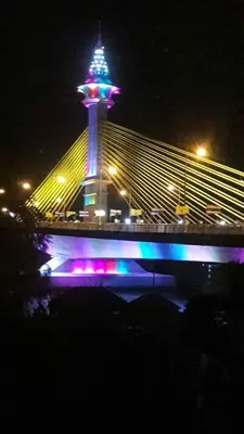 a bridge with a lit up tower on top at night at Baan Anodat in Ban Bang Phai