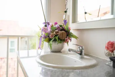 a vase of flowers sitting on top of a sink at Baan Anodat in Ban Bang Phai