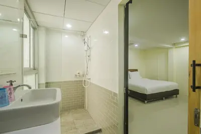 a bathroom with a shower and a sink and a bed at Petchsiri Boutique Hotel เพชรสิริ บูทิค in Bangkok