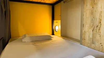 a bed in a room with a yellow wall at Room 22 Hostel - near Chinatown in Bangkok