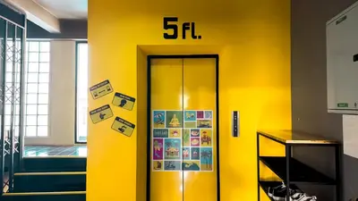 a yellow wall with a elevator with the on it at Room 22 Hostel - near Chinatown in Bangkok